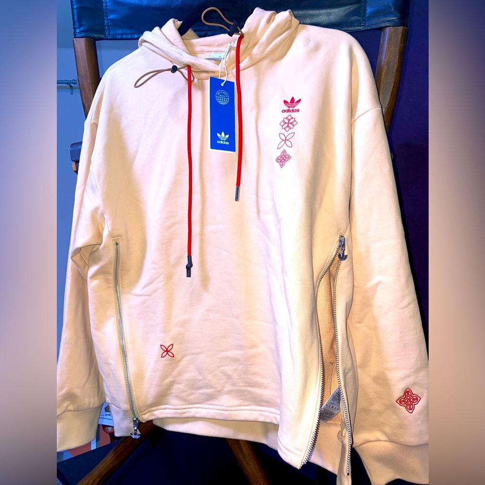 Adidas soft peach hoodie with red embellishments, double zipper front side.